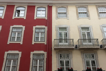 Obraz premium Red and white building front facade with windows and balconies in Lisbon, Portugal. Real estate, urban city, residential area concepts