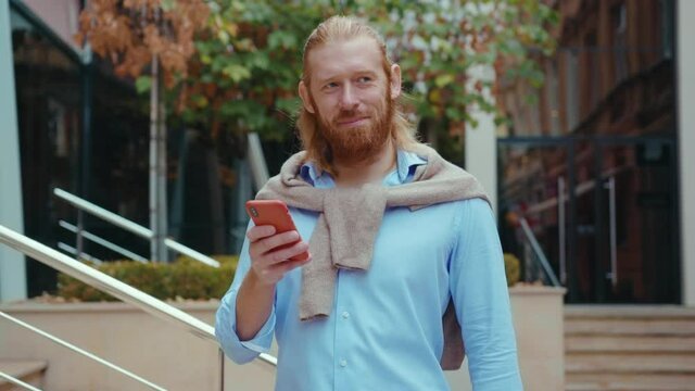 Portrait of good-looking elegant handsome redhead business man using smartphone communication app internet social networking outdoors. Urban concept.