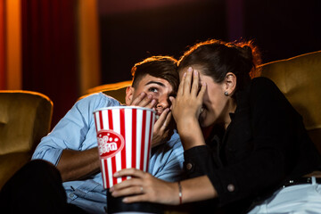 A couple of lovers watching movie shock and eyes close in the movie theater cinema.
