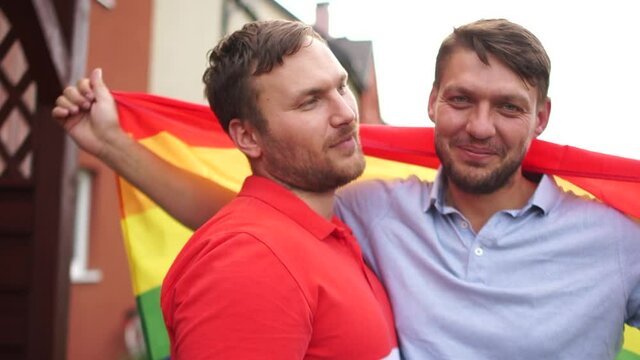 Gay couple. Two young guys hug each other and hold the LGBT rainbow flag. Gay rights, gay marriage