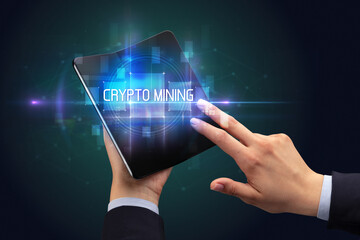 Businessman holding a foldable smartphone with CRYPTO MINING inscription, new technology concept