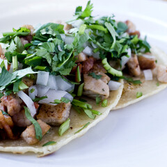 tacos de chuleta de cerdo con tocino cubiertos con cilantro y cebolla