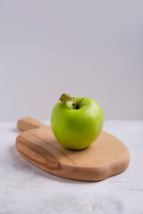 Green apple on a wooden board in the shape of an apple, vertical background with place for copy space. Healthy eating concept