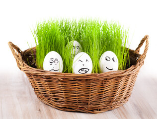 group of Funny crazy smiling eggs in basket with grass. sun bath.