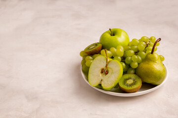  green fruits on the table with copy space, apples, grapes, kiwi, pears. Vegetarianism concept, healthy food. Copy space