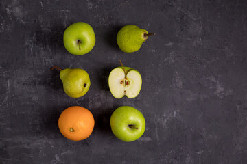 Fruits on a gray textured background. School board. Green apples, pears, oranges. Copy space