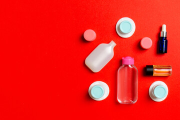 Set of travel size cosmetic bottles on colored background. Flat lay of cream jars. Top view of bodycare style concept