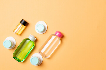 Group of small bottles for travelling on colored background. Copy space for your ideas. Flat lay composition of cosmetic products. Top view of cream containers with cotton pads