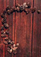 Autumn textured background and plenty of space for text and design. Many small pine cones lie on a mahogany wooden table.