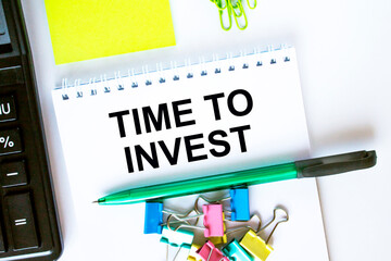 Notepad with text Time To Invest. Calculator, green pen stickers and stationary clips
