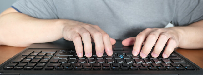 mężczyzna piszący na klawiaturze, laptopie, praca zdalna w domu, biurowa, ręce na klawiaturze,...