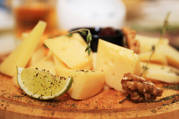 cheese assorted on a round wooden board with a lime tree walnut
