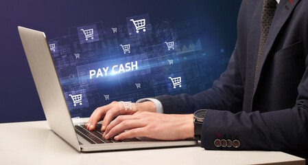 Businessman working on laptop with PAY CASH inscription, online shopping concept