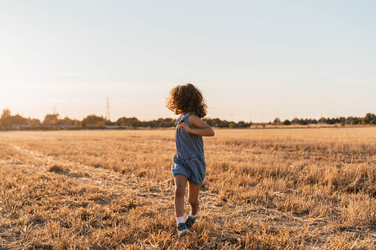 Young Brown Haired Girl Looking Back While Running In The Field