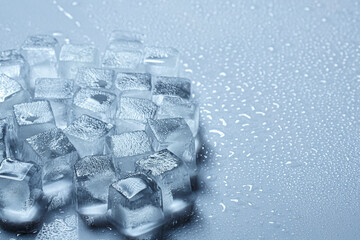 Melting ice cubes are lying on an easy surface. Water droplets of different sizes are nearby. Selective focusing.