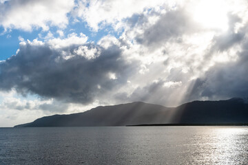 Morning sun-rays illuminating Cairns coastline through the clouds