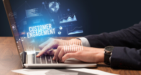 Businessman working on laptop with CUSTOMER ENGAGEMENT inscription, new business concept
