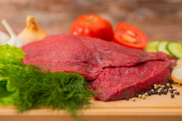raw beef meat with vegetables on wooden plate