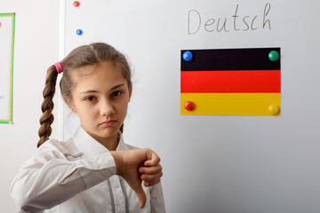 Sad young student of secondary school in white uniform with pigtails is standing in front of board...