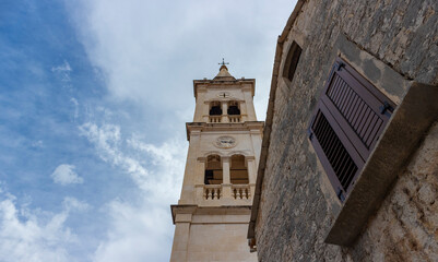 Jelsa/ Croatia-August 7th, 2020: Fascinating fortified church of St. Mary, dating back to 14th century, with bell tower from 19th century rising above the church