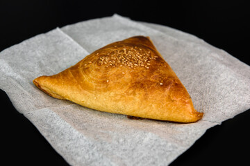 Baking food made of dough stuffed on a platter. Fast food photo subject on a black background.