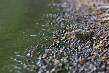 A close up of a beach with small rocks and a bigger one, concept of details and being different.