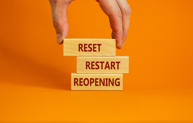 Concept words 'reset, restart, reopening' on wooden blocks on a beautiful orange background. Male hand. Business concept. Copy space.