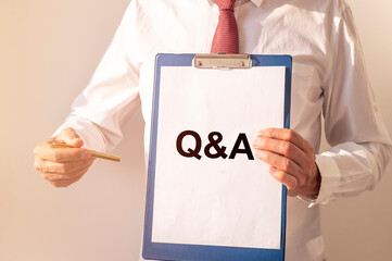 Q and A acronym inscription word on paper card in male hands of businessman