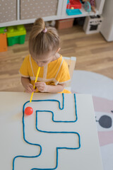 Little girl enjoying game playdough straw maze. Great activity for building oral motor skills at...