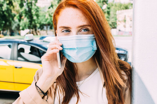 young woman with a face mask makes a call to get a cab