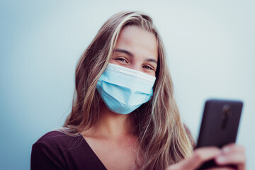 Girl Wearing mask due coronavirus smiles using phone