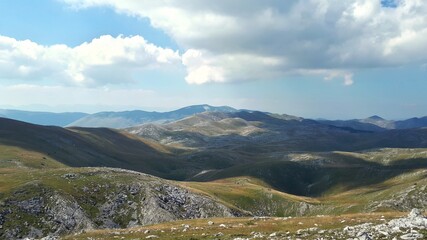 Rocky mountain landscape with sun and clouds