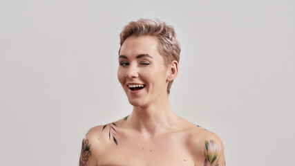 Wink wink. Portrait of a young attractive half naked tattooed woman with perfect skin and makeup...