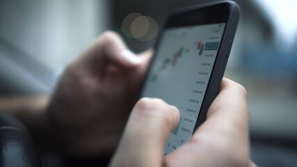 Smartphone with stock market graph on a touch screen device close up, focused shot. Hands with a mobile phone, checking stock market data