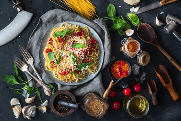 Italian dinner with pasta on ceramic plate with ingredients around on black background. Flat view. Top view.