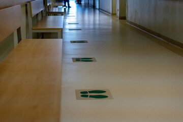 Hospital waiting area: footprint signs on a floor for distance requirements. New normal life, social distancing, coronavirus prevention concept.