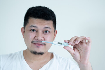 people, healthcare and fever concept - unhealthy asian man measuring oral temperature by thermometer over white background