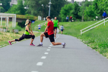 Obraz premium Young couple warming up and stretching together in a park before running