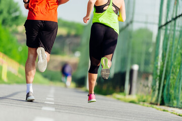 Close up feet with running shoes and strong athletic male and female legs jogging on the running track