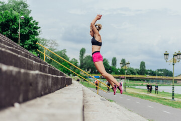 Fit healthy athlete, beautiful woman in tight sportswear jumping on stairs, warming up before...