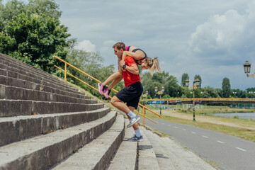 Fototapeta na wymiar Male athlete carrying his female workout partner on his shoulders while running up the stairs