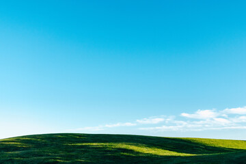 Scenic landscape of green meadow with sunlight and blue sky at background 