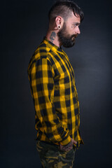 Profile portrait picture of a bearded man with tattoos on his face and neck in yellow black shirt