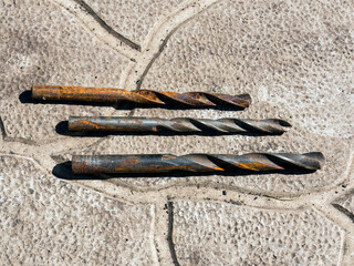 several old rusty drills on a stone background