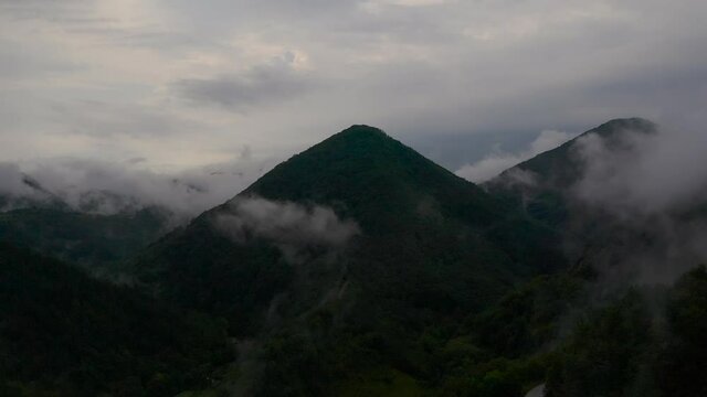 Aerial shot of camera flying through the clouds, towards a mountain that looks like a pyramid.
