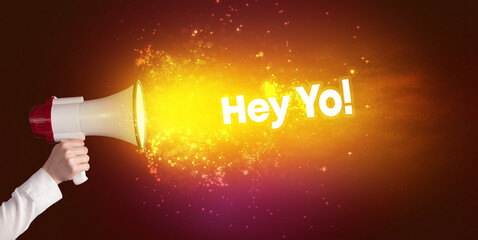 Young woman yelling to loudspeaker with Hey Yo! inscription, modern media concept