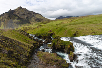view of a river with a mountain in the background and lots of grass