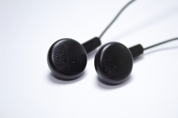 Black earphone with apparent wires and white background