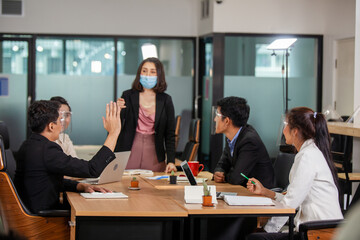 Asain man raising hand to ask question at team training. Audience raising hands up while businessman is speaking in training at the office. young Asian business raising hand during seminar