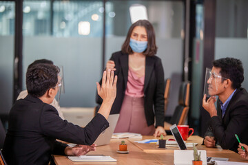 Asain man raising hand to ask question at team training. Audience raising hands up while businessman is speaking in training at the office. young Asian business raising hand during seminar